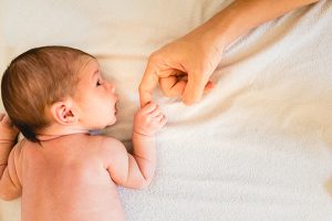 Newborn Baby Securely Grasping His Mother's Hands, Close Up Fingers.