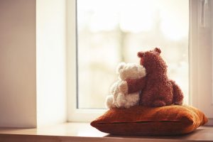 Two Embracing Teddy Bear Toys Sitting On Window Sill