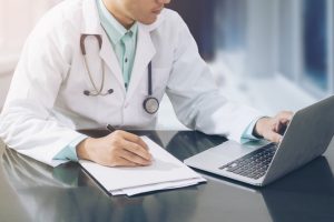 Doctor Working On Desk With Laptop