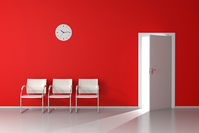 Open Door With Light In Red Waiting Room With White Chairs And W